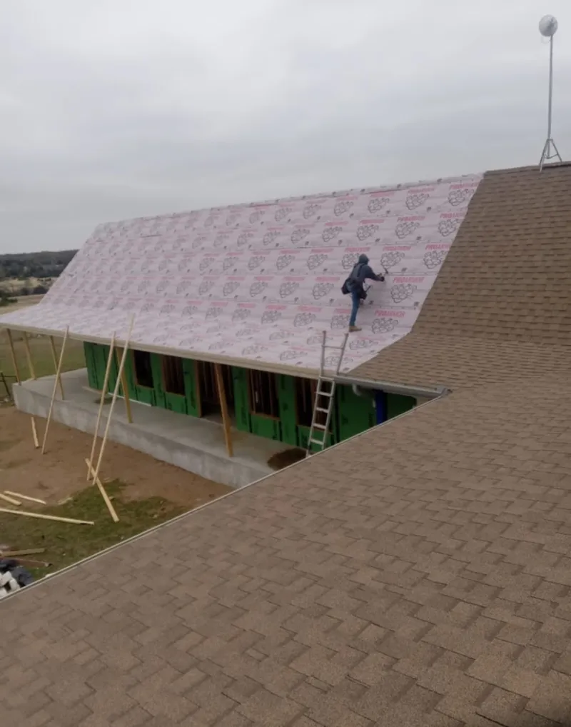 Worker preparing underlayment for a metal roof installation in Kennebunk